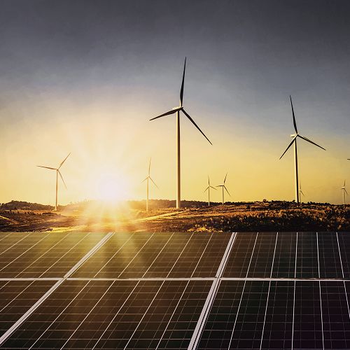 solar panels with wind turbines at sunset