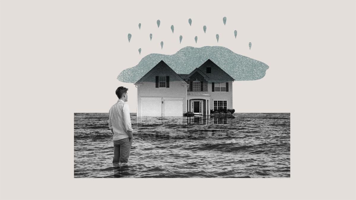 Grist / Getty Images - man standing in front of flooded house