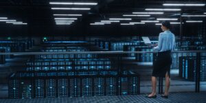 Data center engineer using laptop in server farm cloud