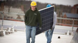 Workers install rooftop solar panels on a Cornell building