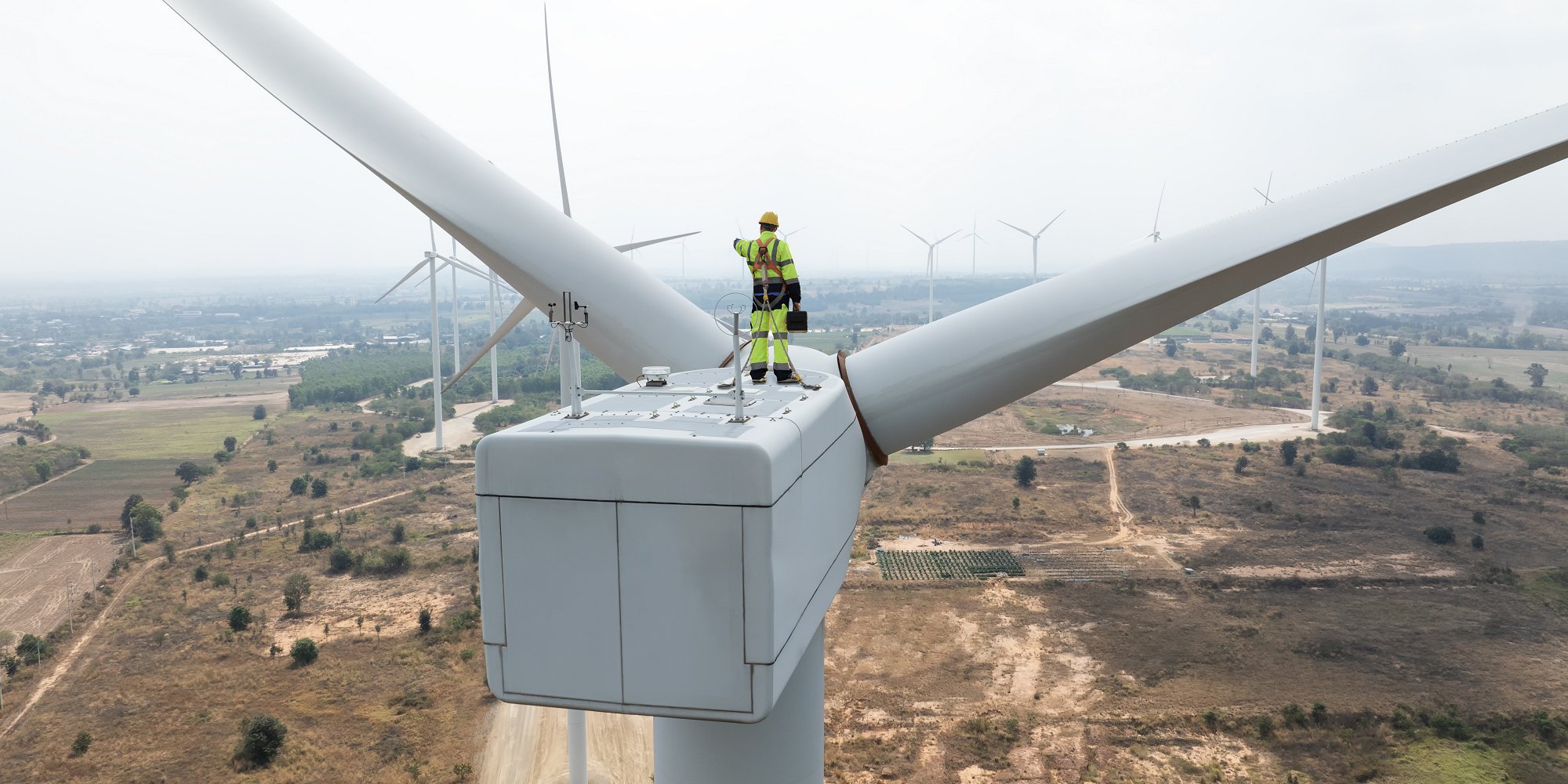 Windmill engineer works on top of wind turbine