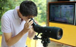 Everett Smith ’27 looks through a telescope at the Lab of Ornithology