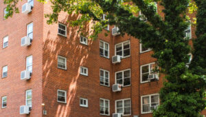 Exterior of apartment building partly shaded by tree