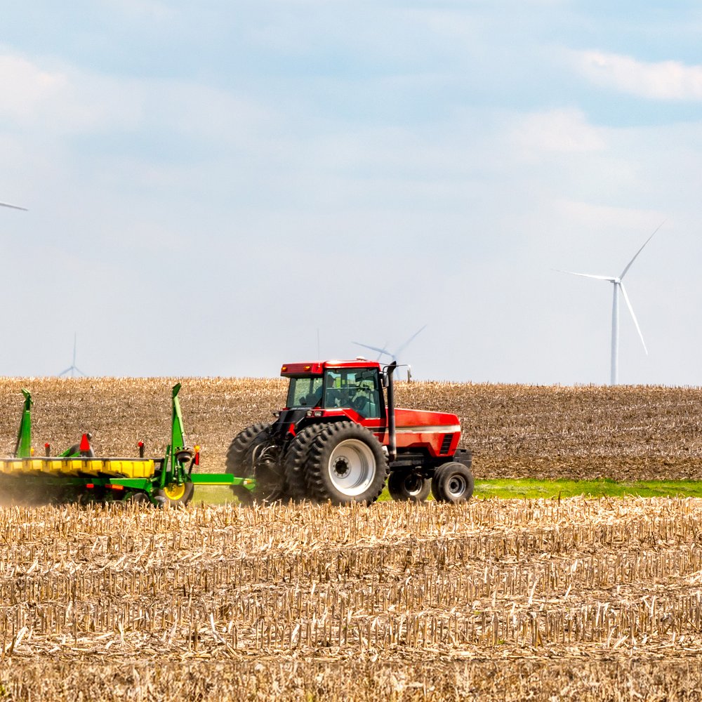 Tractor plowing on farm with wind turbines in the background