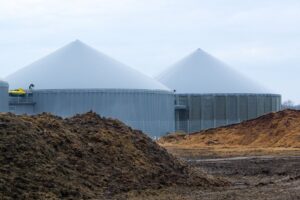 Biogas storage buildings shown behind mounds of manure