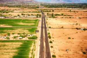 A state highway near Phoenix Arizona, near housing, shows the contrast between dry and semi-irrigated farmland