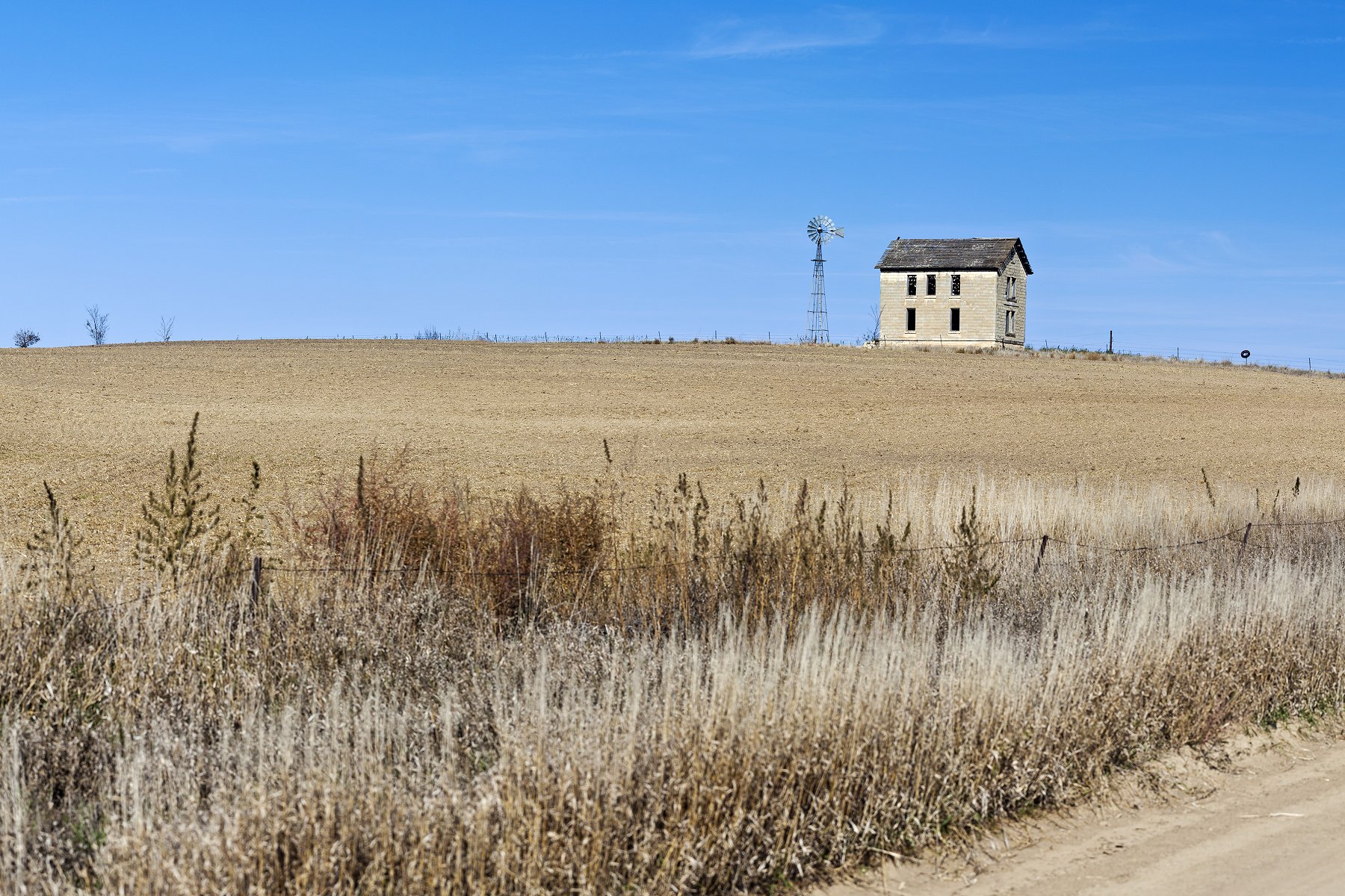 An abandoned home and windmill from rural Kansas with a barren field. Photo taken during the drought of 2012. (iStock)