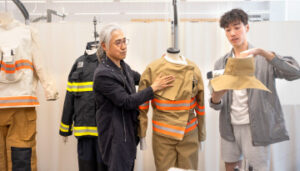 Albert Lin, M.A. ’23, right, displays the new collar for the redesigned fire gear he helped develop along with Heeju Terry Park, left, the Vincent V.C. Woo Professor in the Department of Human Centered Design, and other members of Park’s Performance Apparel Design Lab.